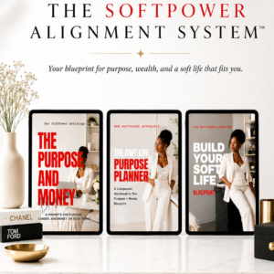 Product mockup for The Softpower Alignment System by Her SoftPower Astrology showing three tablets on a white marble surface with gold trim edge, left tablet displaying The Purpose and Money Blueprint with oversized red title text and a Black woman working at a bright minimal desk, center tablet showing The Soft Life Purpose Planner with a Black woman in an all-cream suit holding a mug in a warm neutral studio, right tablet showing Build Your Soft Life Blueprint with the same woman leaning against a dark marble surface with gold shelving behind her, white ceramic vase with baby's breath flowers and stacked designer books to the left, gold cylindrical vase and black lacquer jewelry box to the right, black serif headline reading The Softpower Alignment System in large spaced capitals above with italic subtitle reading Your blueprint for purpose wealth and a soft life that fits you.
